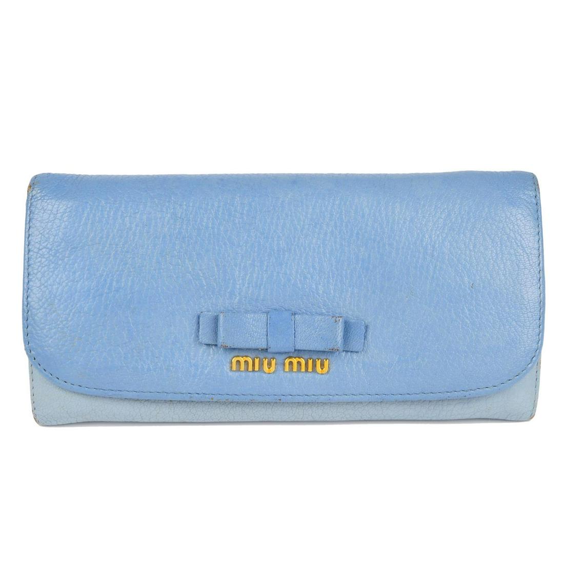 MIU MIU - a Bow wallet. Crafted from two-tone baby blue: MIU MIU - a Bow wallet. Crafted from two-tone baby blue grained leather, featuring maker's gold-tone front logo plaque and leather bow detail, with a rear zip pocket, press-stud fastenings and opening