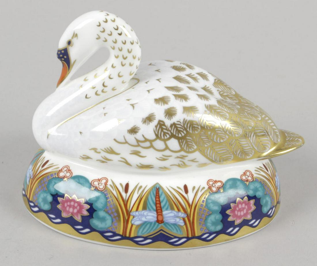 A large Royal Crown Derby paper weight modelled as a: A large Royal Crown Derby paper weight modelled as a swan, the cushion shaped base decorated with dragonflies and bulrushes, the underside with printed marks and inset gold coloured seal, 5.25 (13cm) 