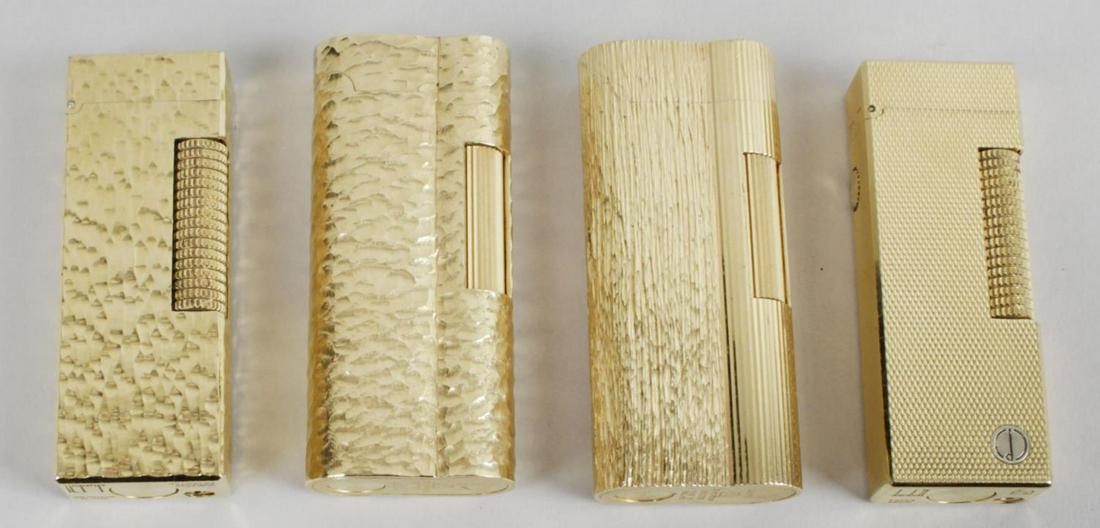 A group of four gold plated Dunhill cigarette lighters,: A group of four gold plated Dunhill cigarette lighters, comprising two examples of rectangular form, and two of rounded rectangular form, each with engine turned and bark effect decoration, each appro