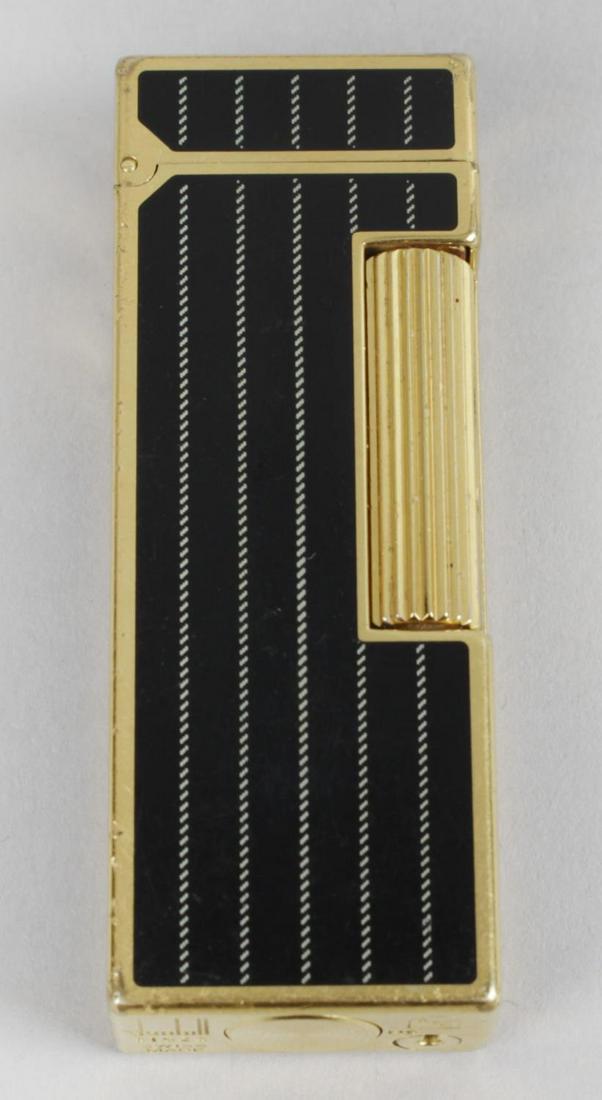 A Dunhill cigarette lighter, of rectangular form with: A Dunhill cigarette lighter, of rectangular form with black lacquer pinstripe effect panelled decoration, 2.5 (6.5cm) high.