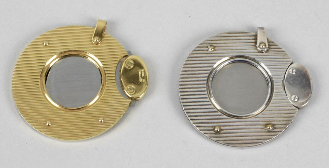 Two Dunhill cigar cutters, the first gold plated: Two Dunhill cigar cutters, the first gold plated example of circular form with vertical banded decoration, the second base metal example of similar form, 1.75 (4.5cm) diameter.