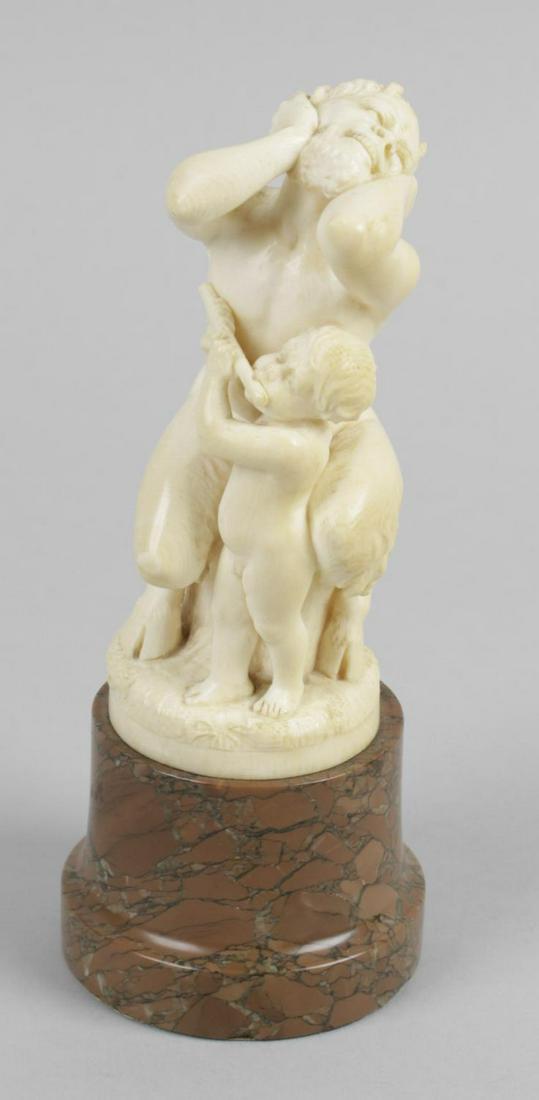 L Kuchler, a 19th century carved ivory figure group,: L Kuchler, a 19th century carved ivory figure group, depicting a satyr with young male infant playing a flute, with engraved signature, raised upon a turned marble column base, ivory 4.5 (11.5cm) high