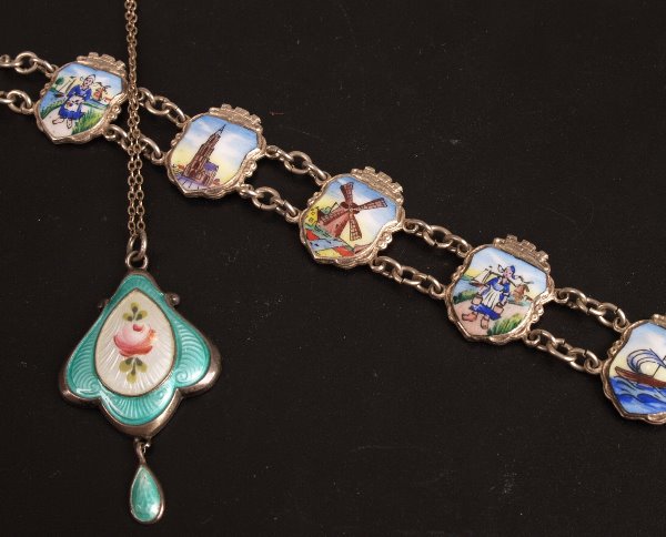 A white metal bracelet with enamelled panels depic