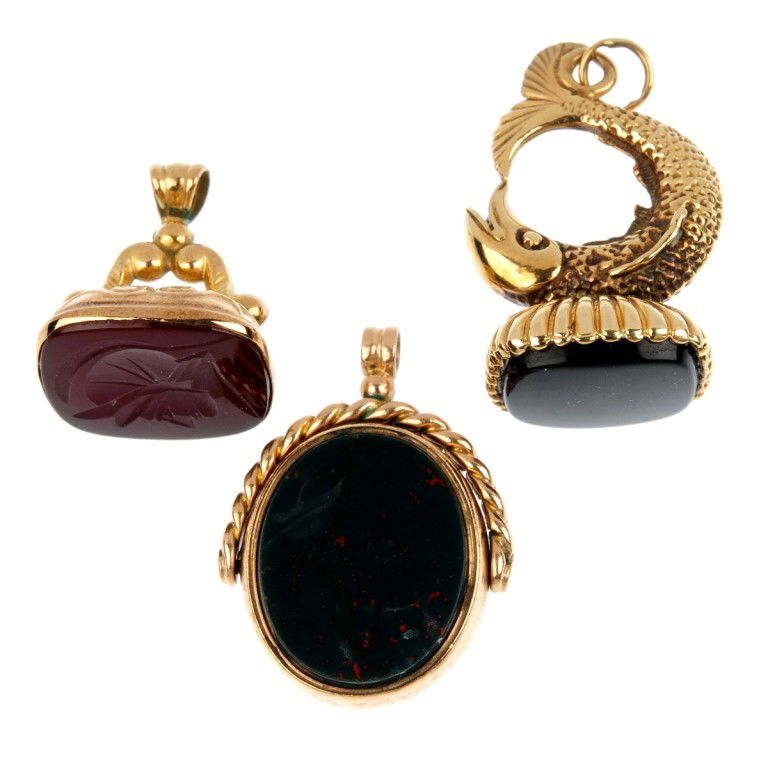 Three gem-set fobs. To include a 9ct gold bloodsto: Three gem-set fobs. To include a 9ct gold bloodstone and cornelian swivel fob, a 9ct gold onyx fob of fish design and a cornelian intaglio fob. AF. Two with 9ct gold hallmarks. One unmarked. Total wei