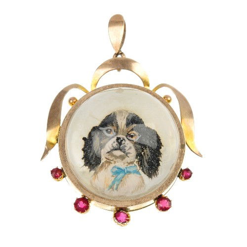 An intaglio dog pendant. The reverse carved intagl: An intaglio dog pendant. The reverse carved intaglio depicting a spaniel to the scrolling openwork surround with circular-shape red gem detail. Stamped 9ct. Length 4.3cms.