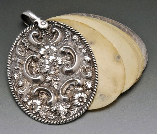 Victorian silver mounted note pad.: Victorian silver mounted note pad of oval form embossed with flowers amongst scrolls, hinge suspension loop and ivory inserts. Hallmarked Thomas Johnson I London 1878. Height measuring 50 mm.