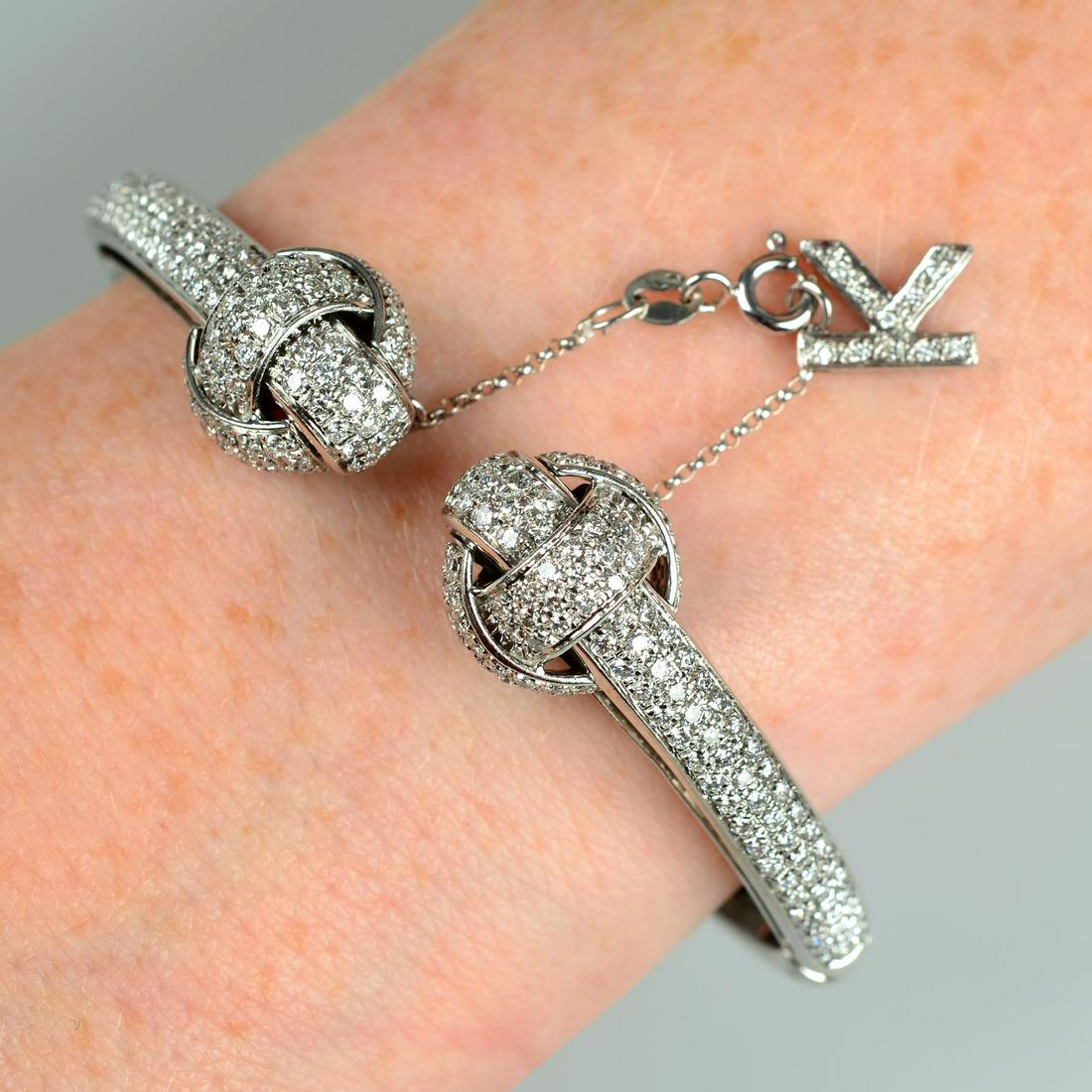 An 18ct gold pavÃ©-set diamond knot motif cuff bangle, with initial 'K' safety clasp, by: An 18ct gold pavÃ©-set diamond knot motif cuff bangle, with initial 'K' safety clasp, by Chimento.Estimated total diamond weight 3cts.Hallmarks for London, 2001. Inner diameter 5.9cms. 35.2gms.