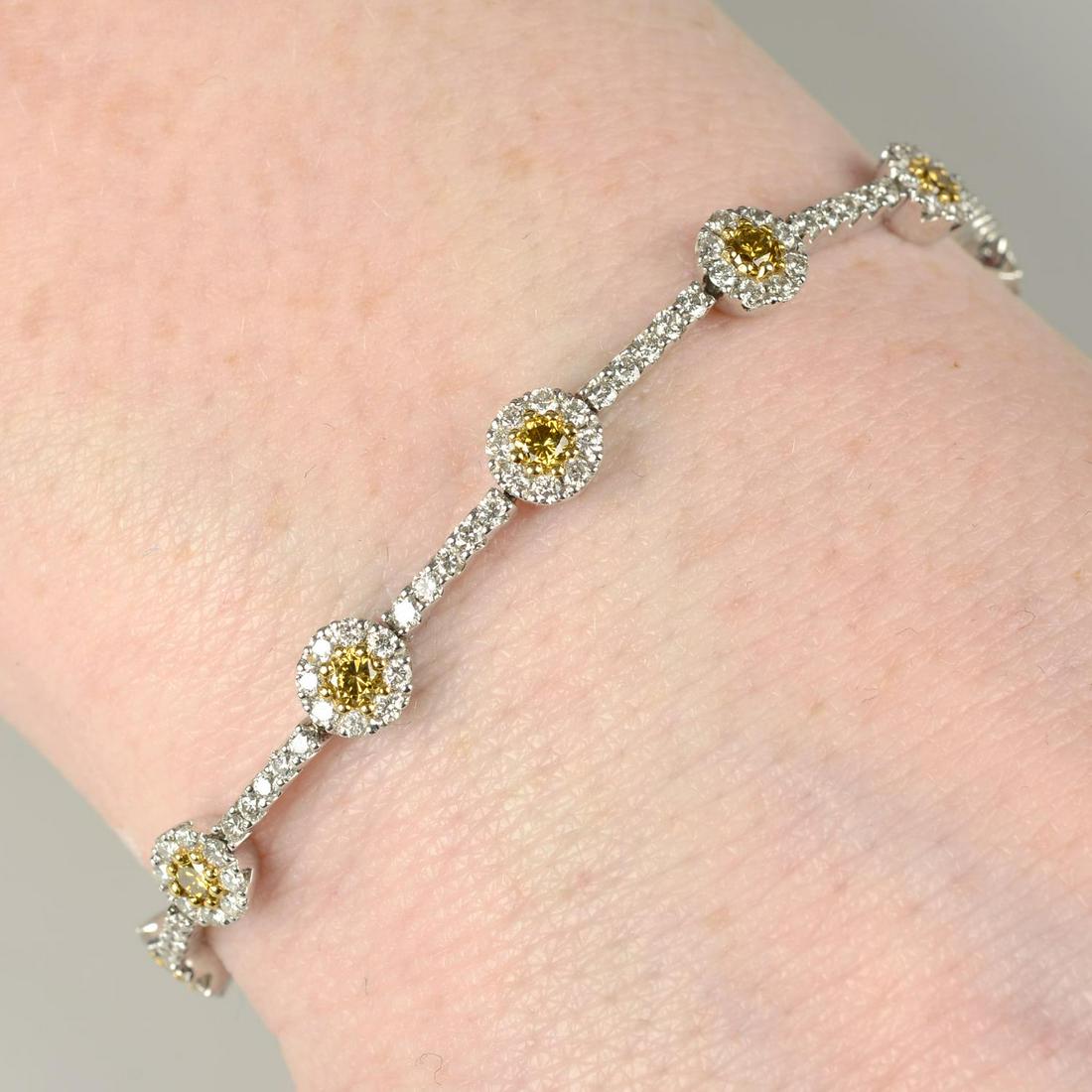 A 'yellow' diamond and diamond cluster bracelet.Total diamond weight 3.41cts, stamped to mount, (1 of 3)