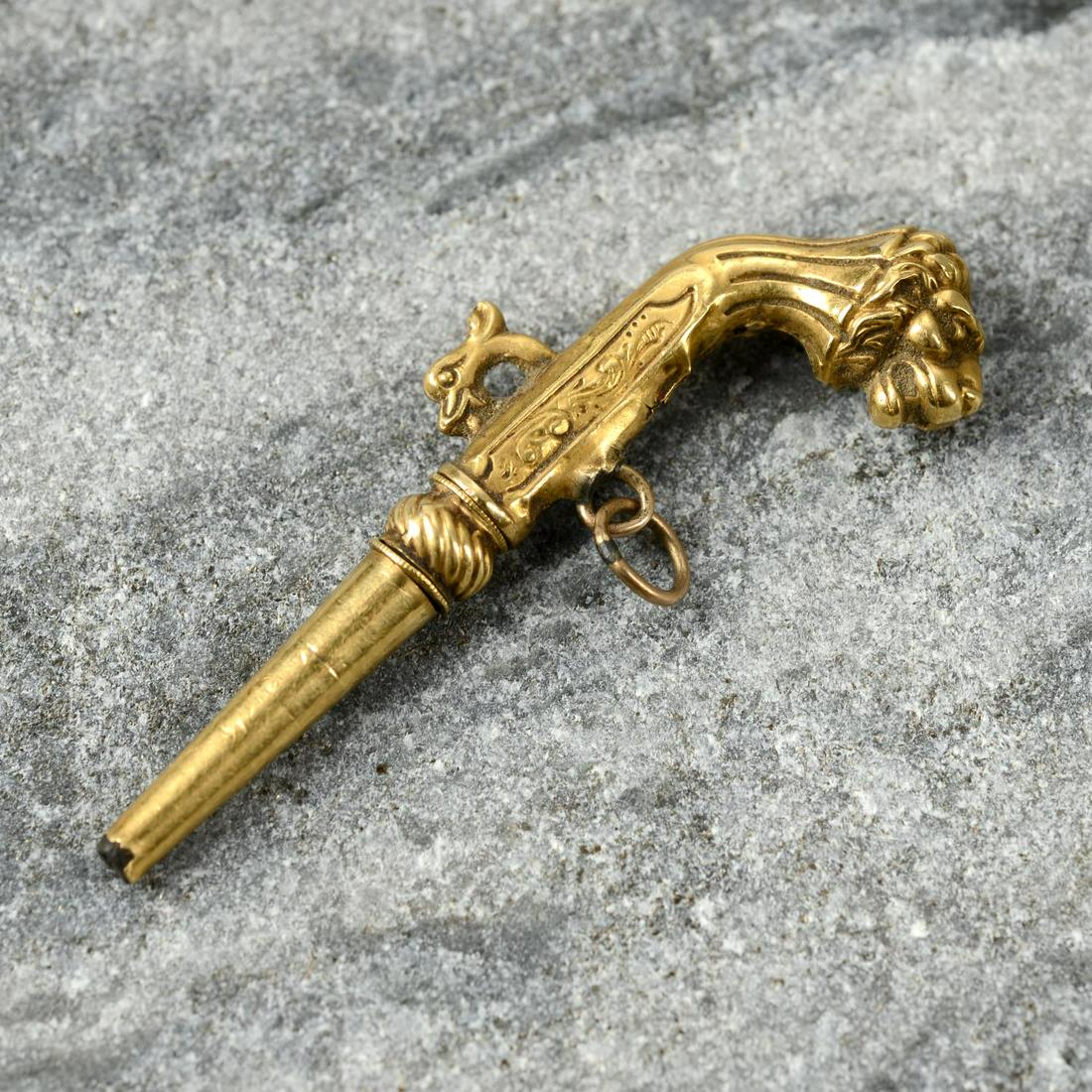 A 19th century 18ct gold watch key, modelled as a pistol with lion head grip.Length 4.9cms. 3.7gms.: A 19th century 18ct gold watch key, modelled as a pistol with lion head grip.Length 4.9cms. 3.7gms.