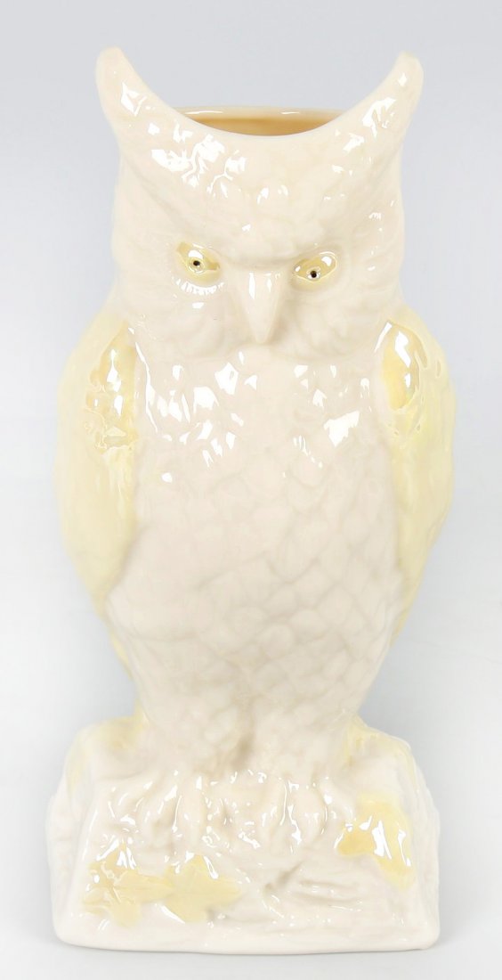 A modern Belleek porcelain vase.: A modern Belleek porcelain vase modelled as an owl perched upon a log. The white glazed body with yellow glazed eyes and wings, green printed marks to base. 8" (20cm) tall.