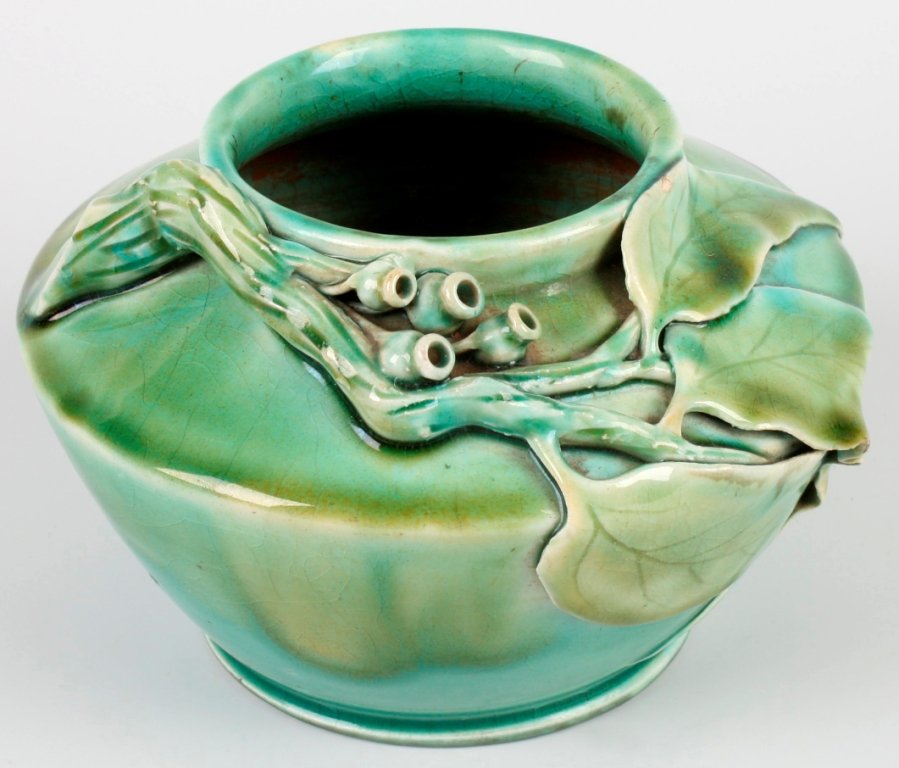 A green glazed Studio pottery pot: A green glazed Studio pottery pot with applied moulded decoration of leaves and stalks, the base inscribed 'Eric Bryce Carter, Sidney'