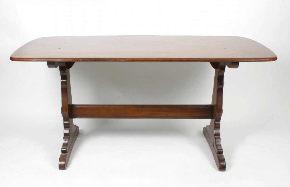An Ercol oak refectory style dining room table: An Ercol oak refectory style dining room table. The shaped rectangular top with rounded edge above a base with shaped panel ends united by a single stretcher. 60" (152.5cm) length, 30" (76.25cm) width