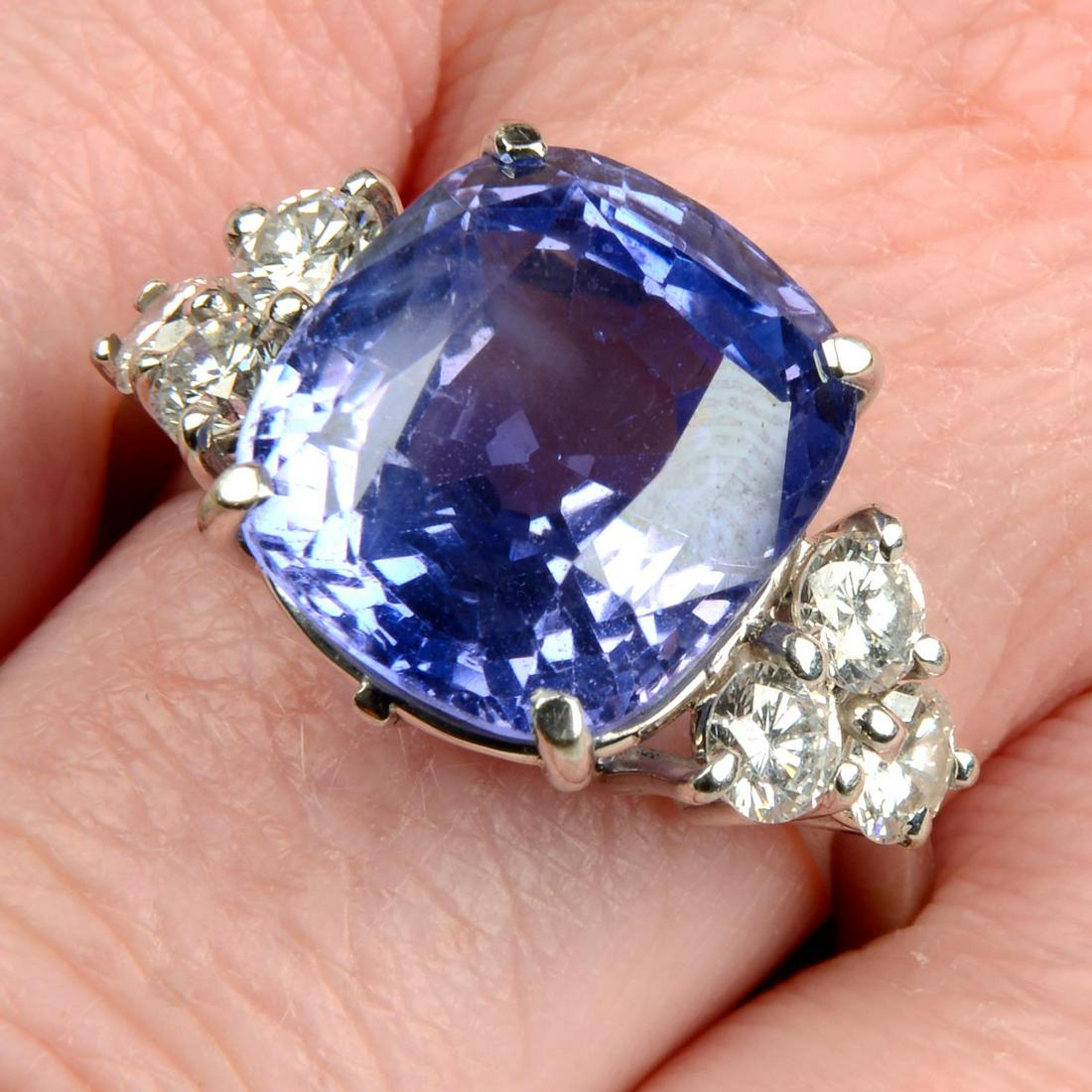 A Sri Lankan colour-change sapphire ring, with brilliant-cut diamond trefoil sides.With report no.: A Sri Lankan colour-change sapphire ring, with brilliant-cut diamond trefoil sides.With report no. 10J2222023, dated March 21st, 2023, from IGI, stating estimated weight 15cts, colour change from blue