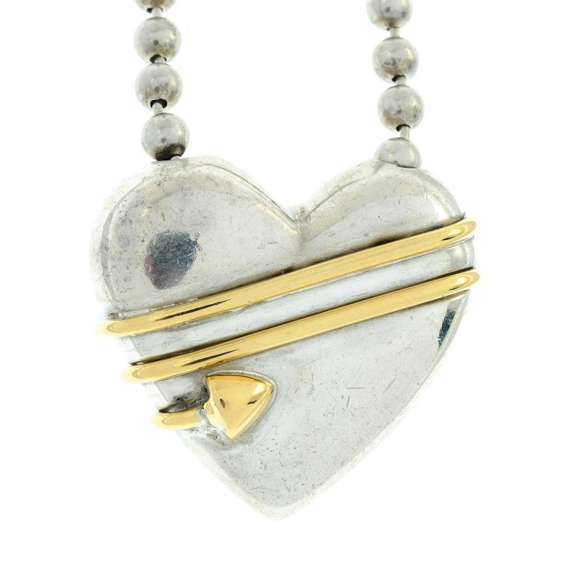 A heart pendant, with arrow motif, on a bead-link chain, by Tiffany & Co.: A heart pendant, with arrow motif, on a bead-link chain, by Tiffany & Co. Signed Tiffany & Co. Pendant stamped 925 750, chain stamped 925. Length of pendant 1.8cms. Length of chain 44.5cms. To