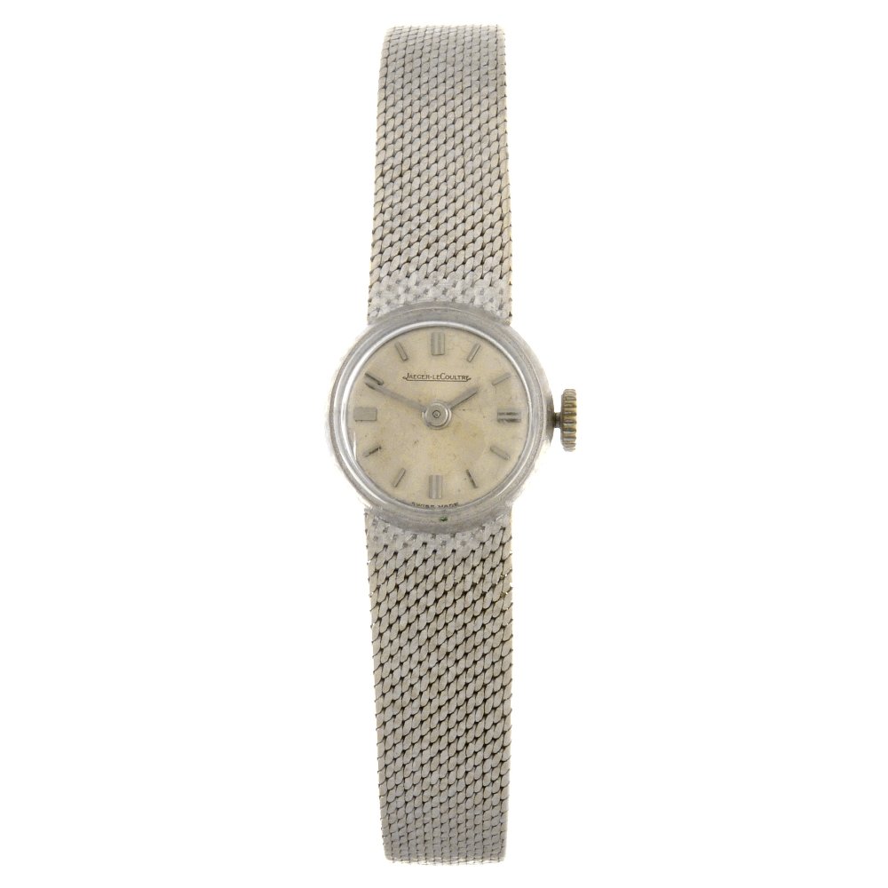 An 18k white gold manual wind lady's Jaeger-LeCoult: JAEGER-LECOULTRE - an 18k white gold manual wind lady's bracelet watch, the silvered dial with baton hour markers, circular shaped case, stamped with poincon, fitted to an integral bracelet, signed mo
