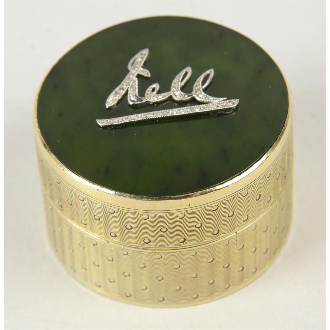 An early 20th century silver-gilt pill box.: An early 20th century silver-gilt pill box, of engine-turned circular form, and removable hardstone lid with applied name detail inset with rose-cut diamonds. Hallmarked Frederick Thomas Buckthorpe, L