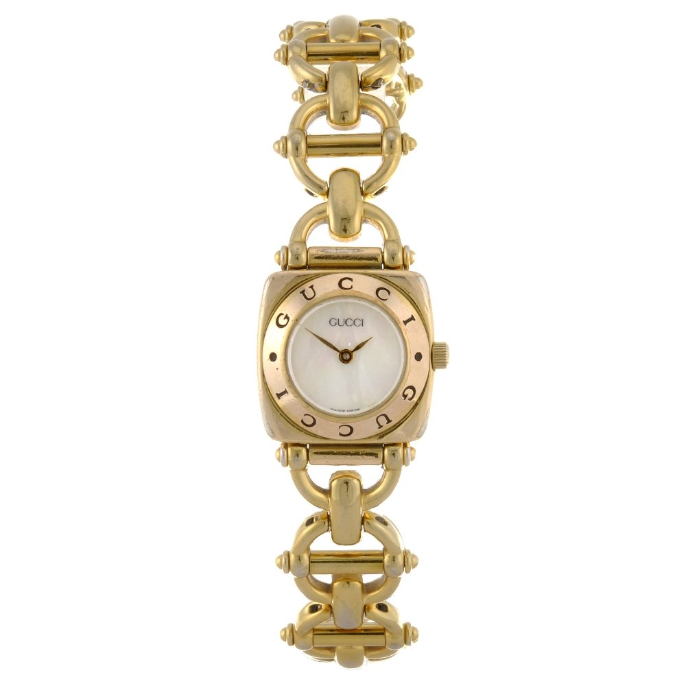A gold plated quartz lady's Gucci 6400L bracelet wa: GUCCI - a gold plated quartz lady's 6400L bracelet watch, the plain mother of pearl dial, cushion shaped case, fitted to a fancy link bracelet with clasp. Case width 22mm.