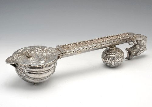 An Asian ornamental sitar condiment.: An Asian white metal ornamental sitar condiment, modelled as a sitar with animal and foliate designs, the body opening up to reveal compartments for various condiments, unhallmarked. Maximum length 18