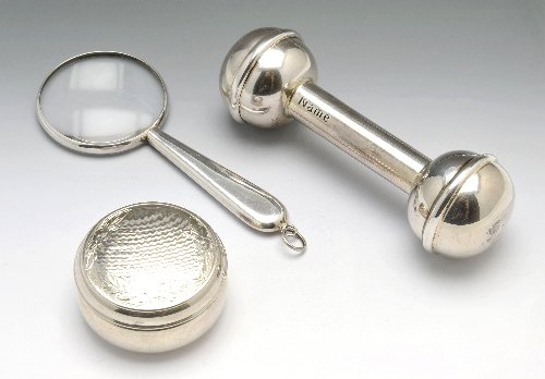 A modern silver child's rattle modelled as a dog's: A modern silver child's rattle modelled as a dog's bone with space for name, date and weight personal engravings, hallmarked Birmingham 2000. Together with a modern silver pill box with floral and eng