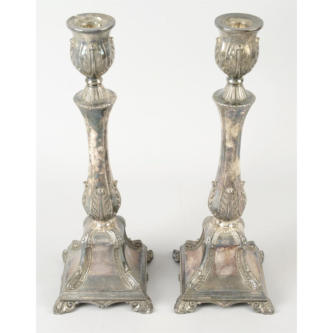 Pair of Hazorfim candlesticks; together with a singular candlestick.: A pair of Hazorfim candlesticks, the tapered, square base upon plumed stepped feet, with decorative plumed, engraved and beaded detail to each corner, rising to panelled stem with acanthus border and