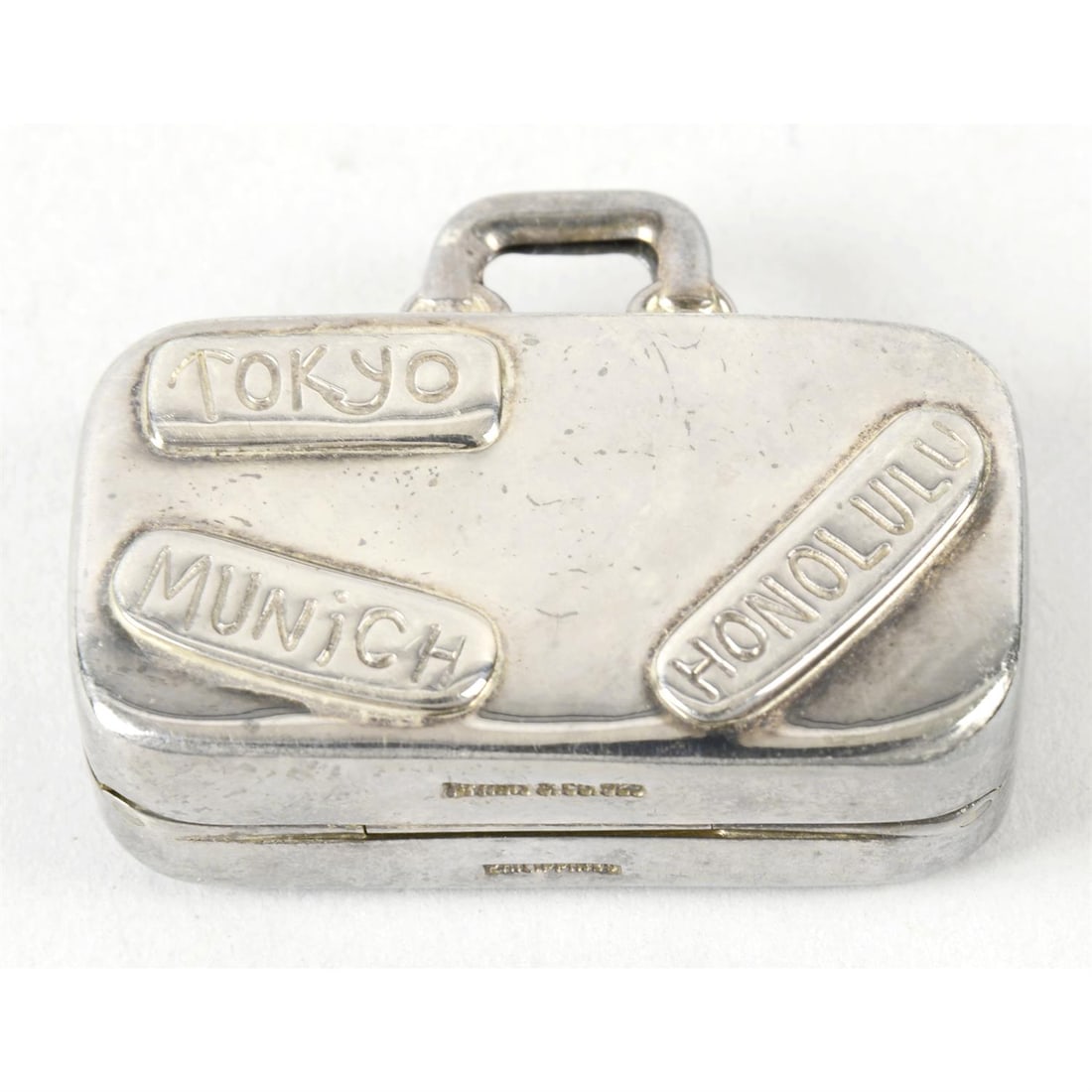 A Tiffany & Co sterling silver novelty pill box modelled as a suitcase.: A Tiffany & Co sterling silver novelty pill box modelled as a suitcase. Stamped T&Co 925. Length 4.5cm, weight 1.14 ozt (35.6g). Condition Report: Item shows general surface scratches, marks, wear, an
