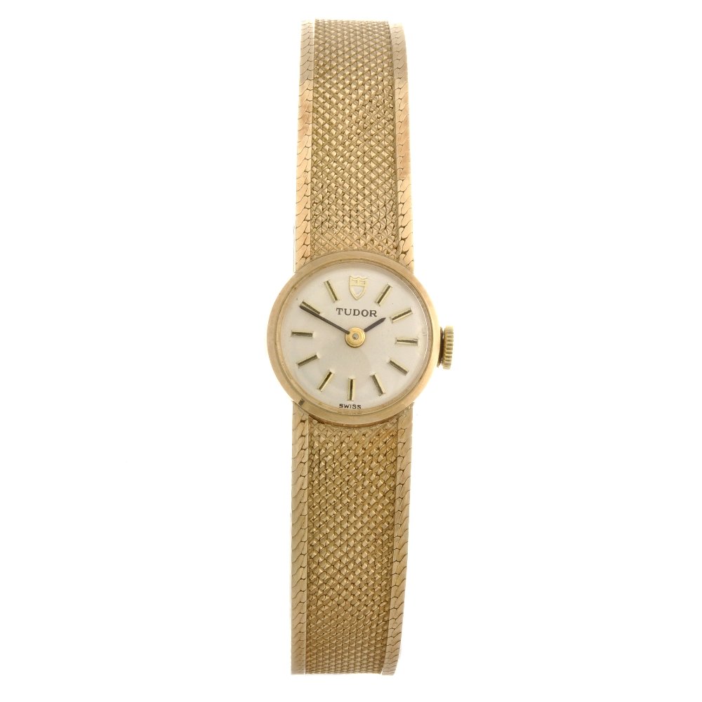 A 9ct gold manual wind lady's Tudor bracelet watch: TUDOR - a 9ct gold manual wind lady's bracelet watch, the silvered dial with hourly applied gilt batons, round case, fitted to an integral 9ct gold bracelet with folding clasp, hallmarked Birmingham 1