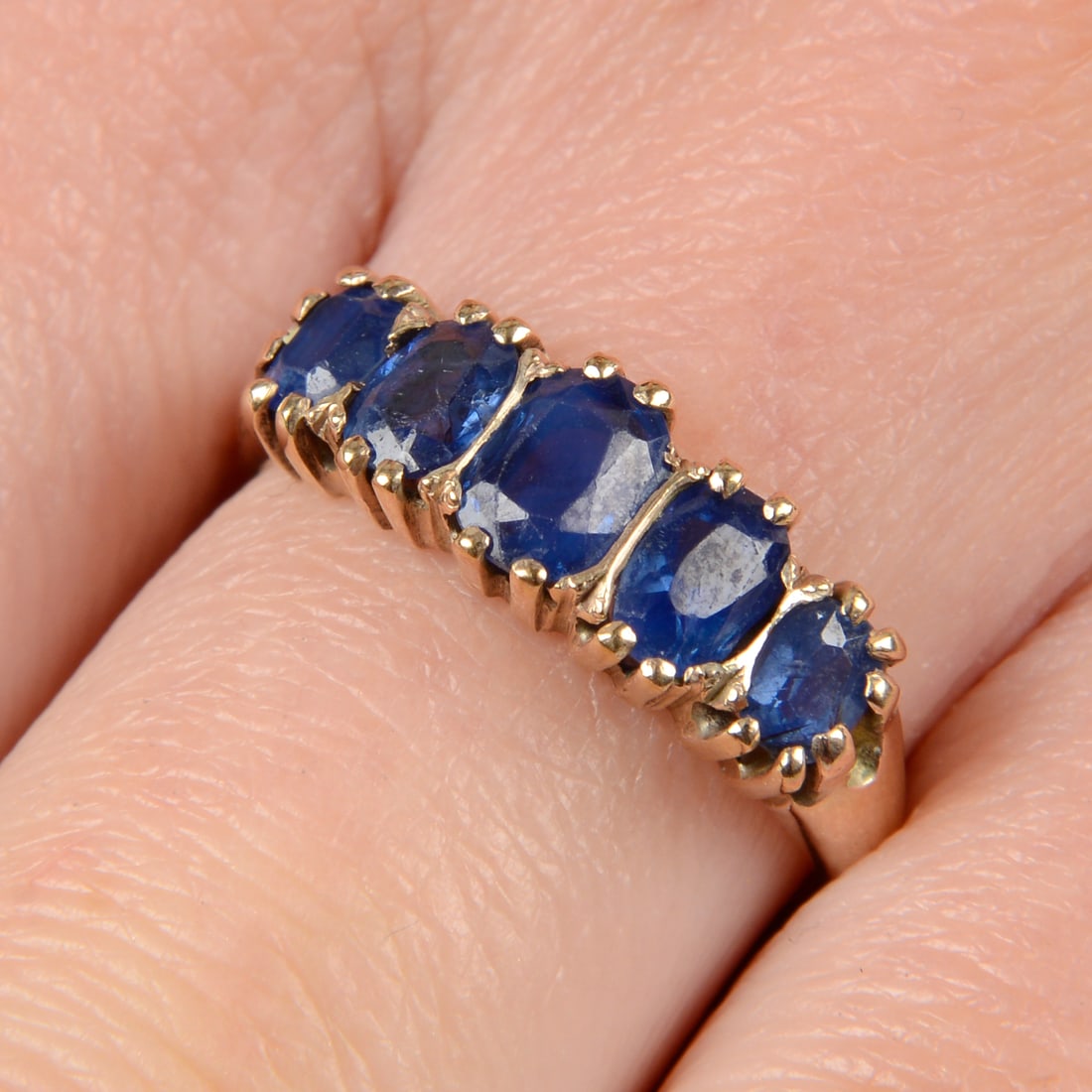 A late Victorian gold graduated sapphire five-stone ring. Central sapphire calculated weight 0.70ct, (1 of 4)