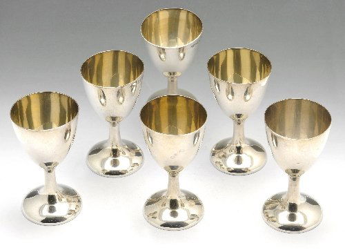 Early 20th century set of six silver tot cups & two egg: Early twentieth century set of six silver tot cups of plain goblet form, hallmarked Joseph Gloster Ltd., Birmingham 1916; together with a small oval tray, hallmarked Birmingham 1918, same maker, a sin