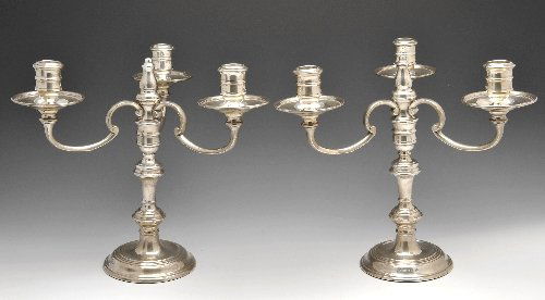 A pair of modern silver mounted three branch candelabra: A pair of modern silver mounted three branch candelabra, each raised above circular stepped bases, to the baluster stems and triform scrolling branches with urn shaped sockets, loaded. Hallmarked Garr