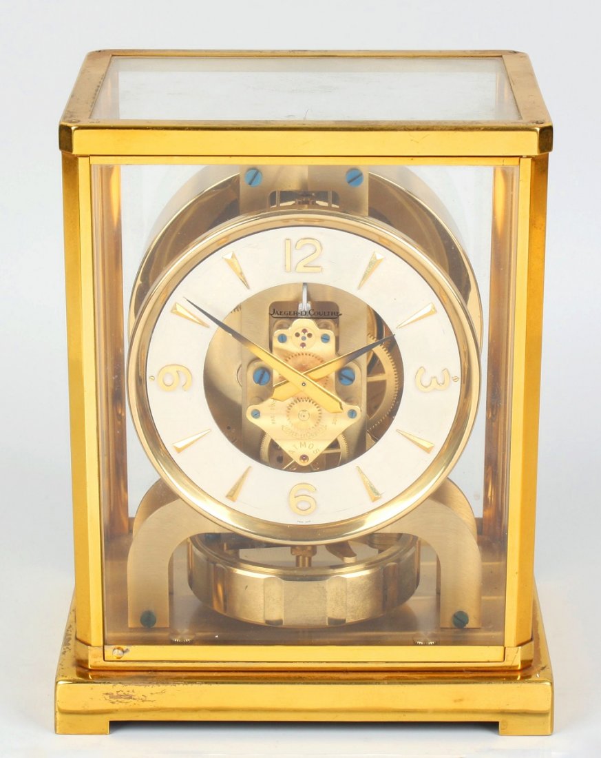 A Jaeger LeCoultre 'Atmos' clock: A Jaeger LeCoultre 'Atmos' clock. Having a silvered chapter ring with Arabic quarters framing exposed movement and dagger batons, the movement numbered 89173, in a canted lacquered brass case, dedicat