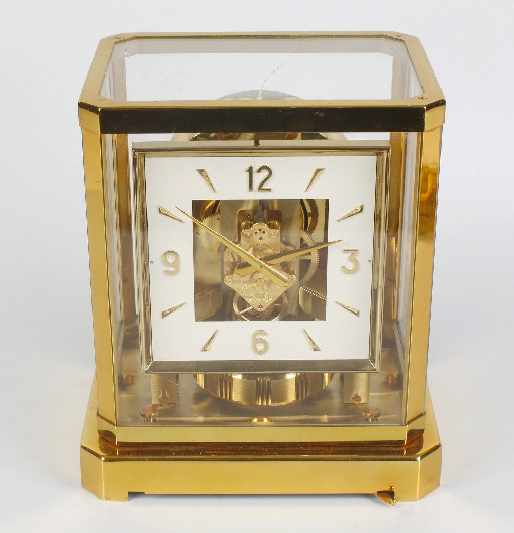 A Jaeger LeCoultre Atmos clock: A Jaeger LeCoultre Atmos clock. Having a a 5" square dial with gilt Arabic quarters, dagger residual hours and batons, framing an exposed mechanism, the escapement numbered 125939, in a canted lacquer