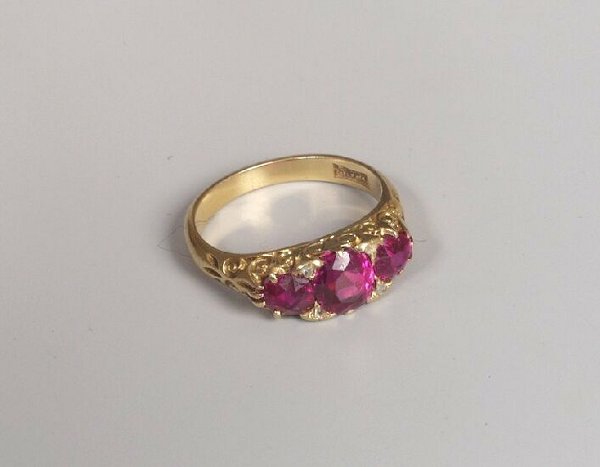 Late Edwardian 18ct gold three stone ruby: Late Edwardian 18ct gold three stone ruby carved half hoop ring with rose cut diamond points. The rubies are of a rich pinky red, (some abrasion to the facets).