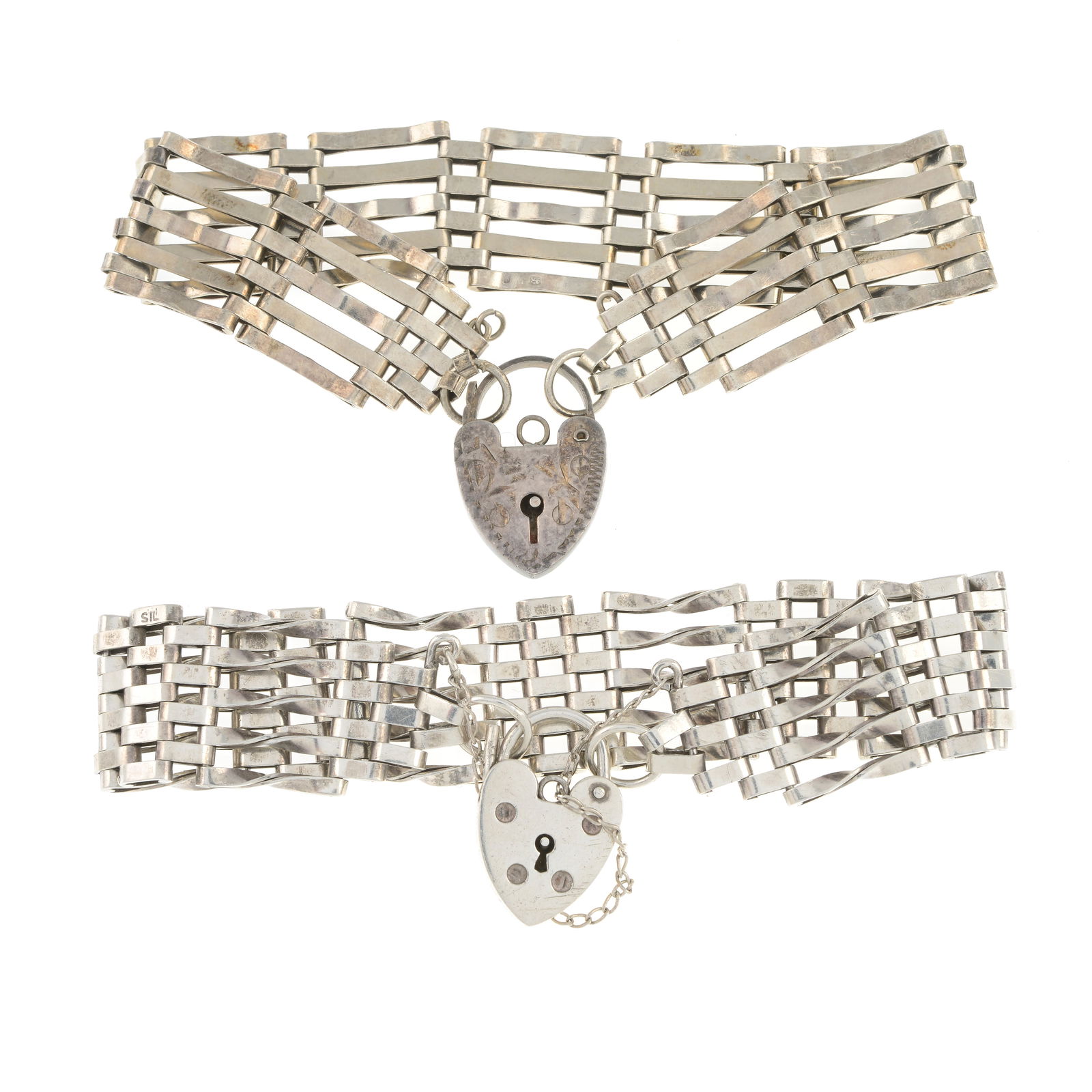 Two gate-link bracelets with heart padlock clasps: Two gate-link bracelets with heart padlock clasps One with hallmarks for London, indistinct date letter. One stamped Silver. Lengths of bracelets 17 and 18cm. Condition Report: Metal with s