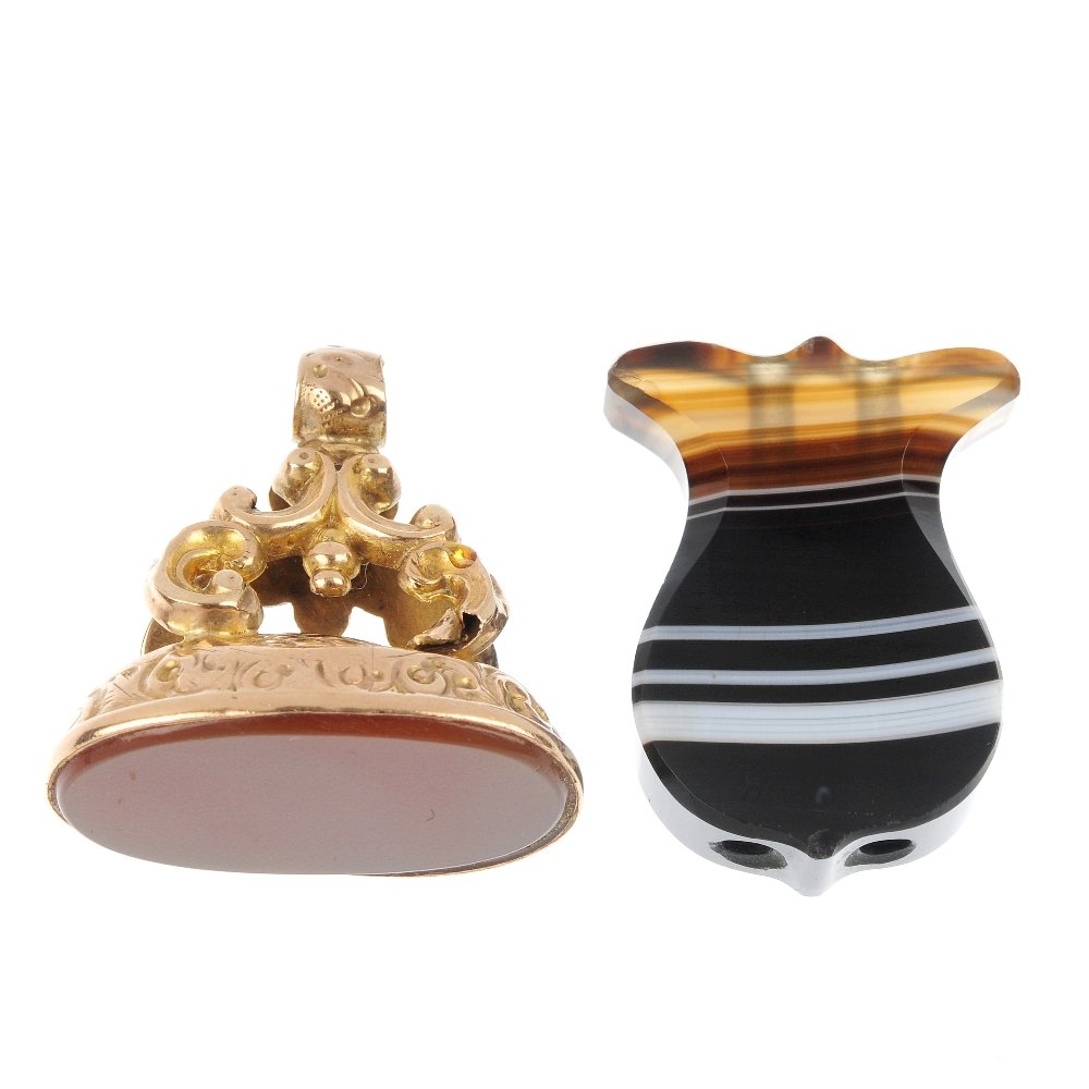 An early 20th century gilt fob and a agate panel.: An early 20th century gilt fob and a shield-shape agate panel, the first set with an oval carnelian panel to the scrolling pedestal, the second banded agate panel of shield-shape outline. Length of fo