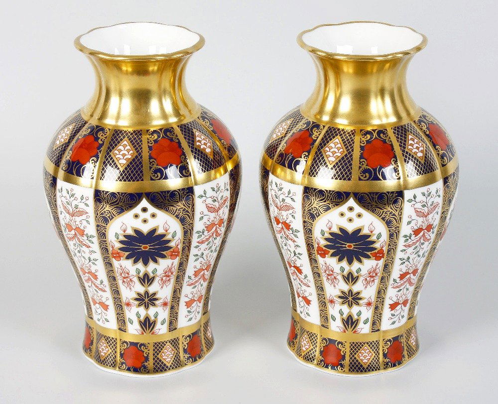 A pair of Royal Crown Derby bone china vases: A pair of Royal Crown Derby bone china vases each of baluster shaped form with a white glazed ground, gilded necks and old Imari decorated bodies and red printed marks to bases, each 8" (20cm) tall