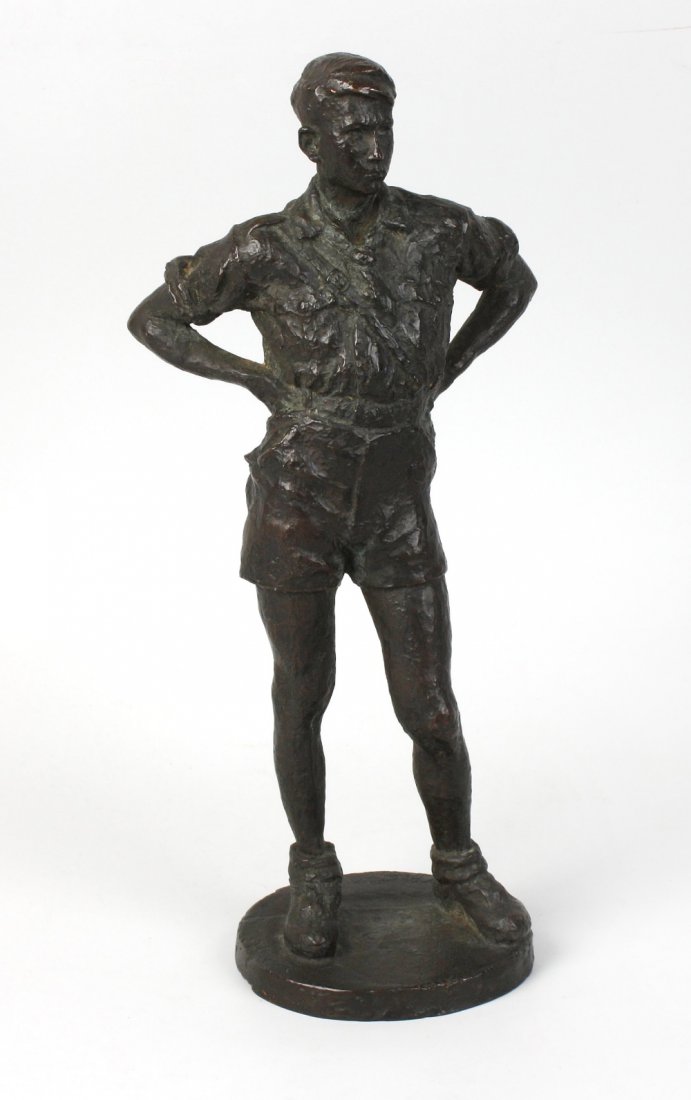 A 20th century cast bronze figure: A 20th century cast bronze figure modelled as a young man in standing pose with hands resting upon his hips, dressed in military style shirt and shorts, believed to be Hitler youth, on circular natura