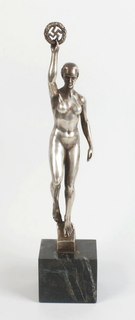 After Josef Thorak, (1889-1952): After Josef Thorak, (1889-1952). A silvered bronze figure of Victory, modelled as a naked female holding aloft a wreath with Nazi swastika to centre, modelled in standing pose on a canted base cast ve