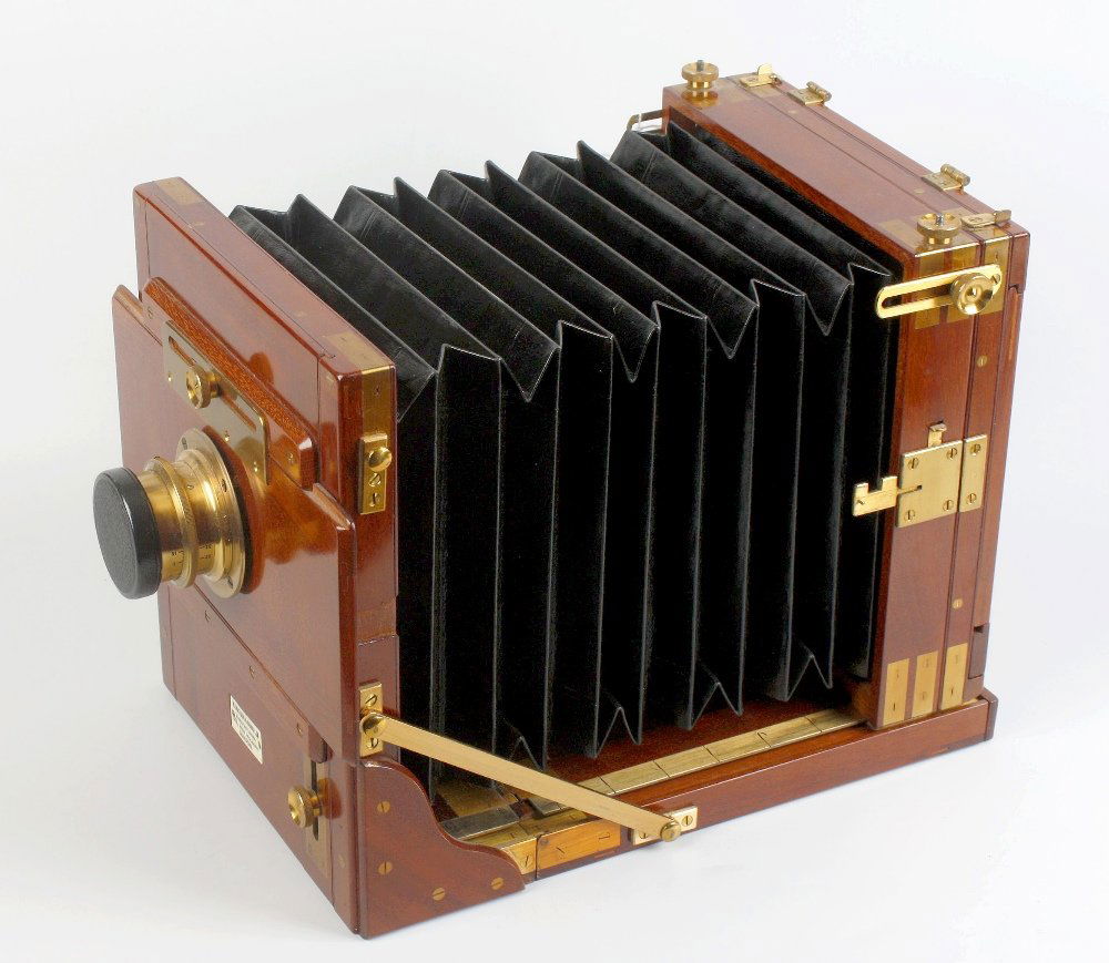 A Watson & Sons brass and mahogany half plate camera: A Watson & Sons brass and mahogany half plate camera. With Ross F.11 Focus 11 1/4 in. Patent lens No. 104773, refurbished black morocco bellows and lacquered fittings, ivory plaque of 'W. Watson & Son