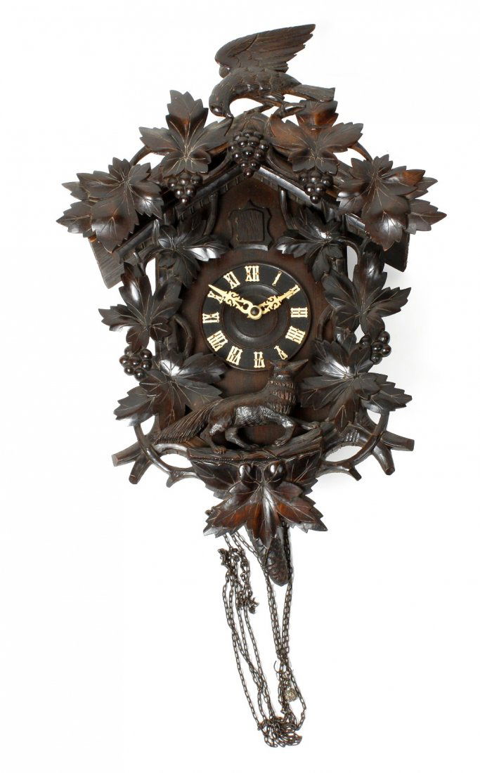 A Black Forest cuckoo clock: A Black Forest cuckoo clock. With gothic black letter dial beneath cuckoo shutter, the two-train spring-driven movement surmounted by twin bellows, the chalet case with carved bird and fruiting vine c