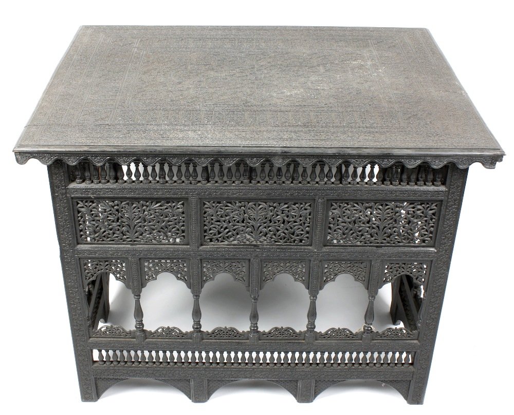 An unusual Indian carved ebony folding table: An unusual Indian carved ebony folding table. The moulded rectangular top finely and densely carved with a central flowerhead amidst arabesques, within multiple borders of shaped mihrabs or niches, fl