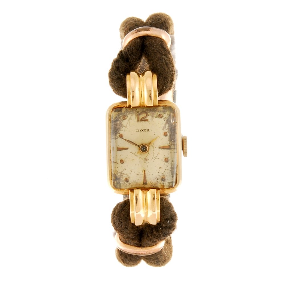 An 18k gold manual wind lady's Doxa wrist watch.: DOXA - an 18k gold manual wind lady's wrist watch, the silvered dial having copper tone hour markers and Arabic numeral to twelve o'clock, the rectangular shaped case, stamped 18k with poincon, fitted