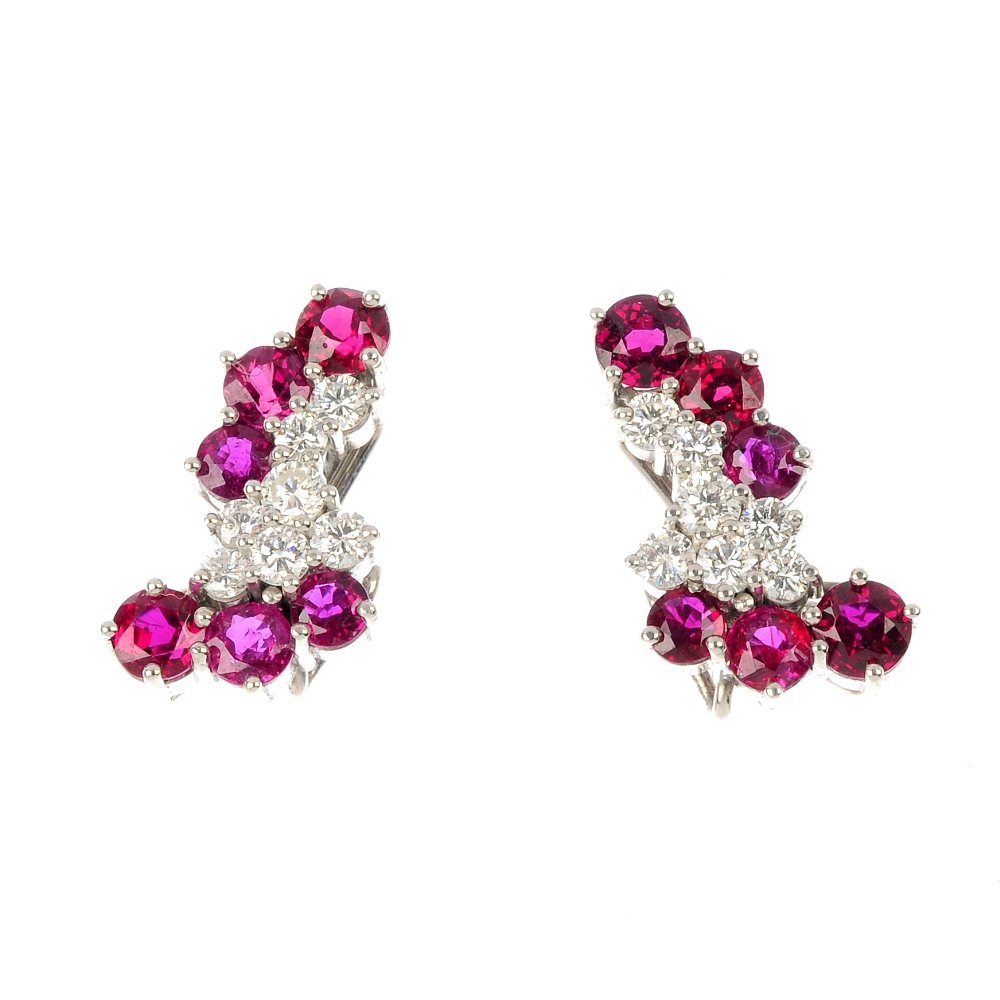 A pair of ruby and diamond earrings.: A pair of ruby and diamond earrings. Each designed as a brilliant-cut diamond abstract cluster, with graduated circular-shape ruby line accents. Estimated total diamond weight 0.70ct. Length 1.9cms. W