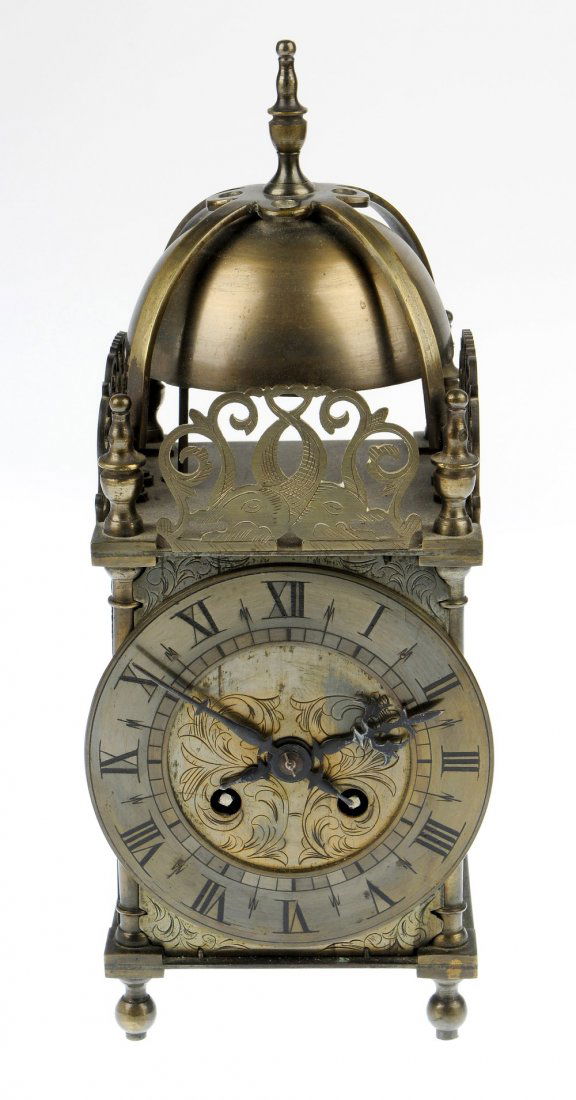 A reproduction lantern clock: A reproduction lantern clock, The French two-train movement striking on a strapped bell, over pierced crestings, Roman dial with half hour divisions, and turned feet, 11.5", (29cm) high.