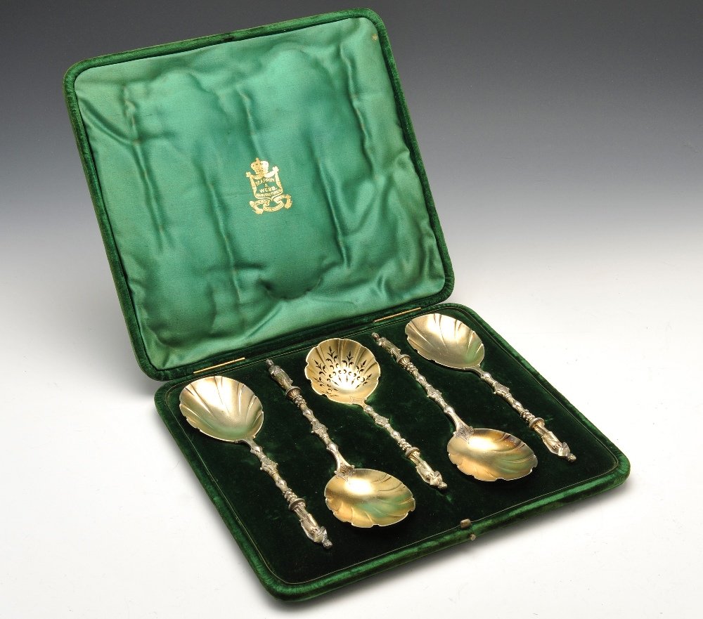 A Victorian cased set of four silver-gilt fruit spoons : A Victorian cased set of four silver-gilt fruit spoons with sugar sifter, each with oval shallow fluted bowls to the shaped decorative stems and figural terminals, personal initials engraved to the re