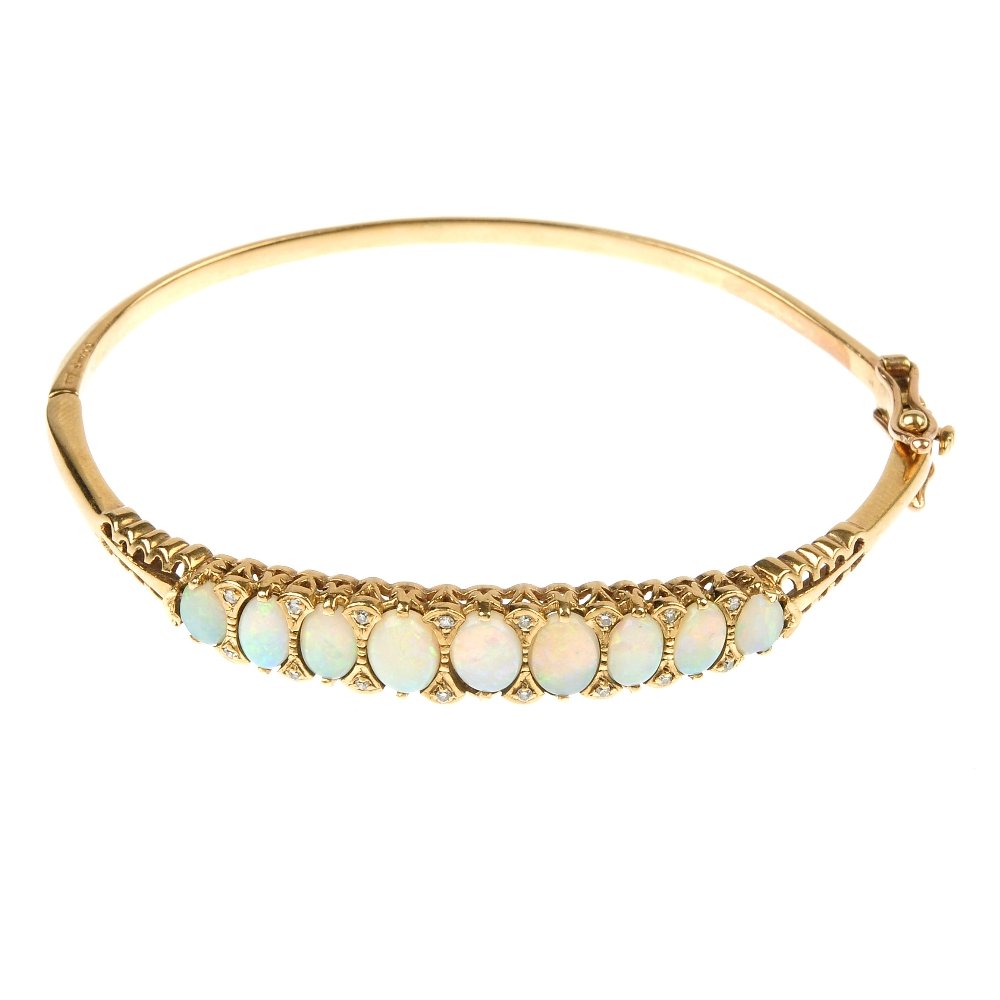 A 9ct gold opal and diamond bangle.: A 9ct gold opal and diamond bangle. The front designed as a series of oval opal cabochons, with single-cut diamond double spacers, to the plain half-bangle. Estimated total diamond weight 0.15ct. Hall