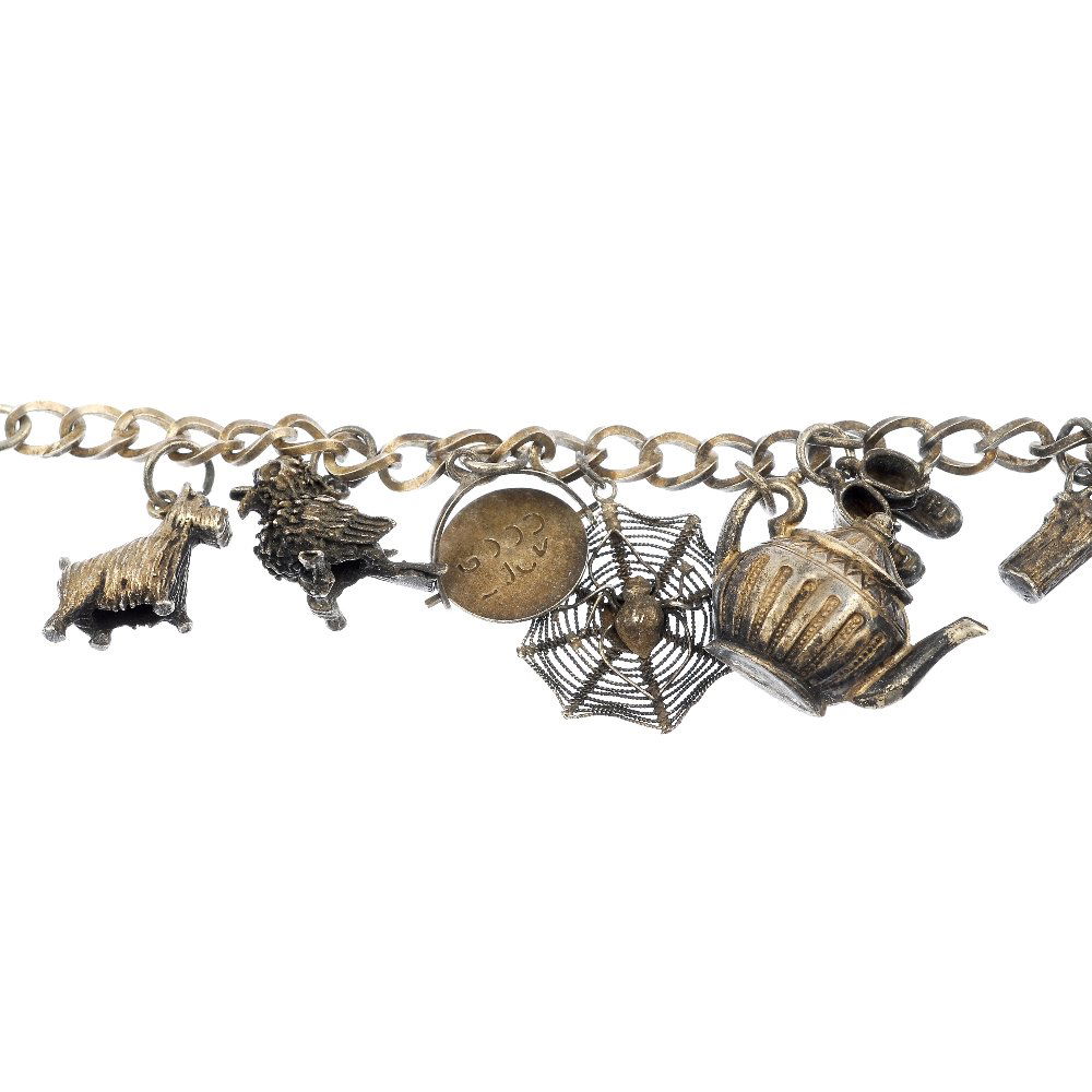 A selection of three silver and white metal charm: A selection of three silver and white metal charm bracelets. Comprising a total of thirty-five charms, to include a top hat, a bird and a letter box, to the curb-link chains. Two chains with partial h