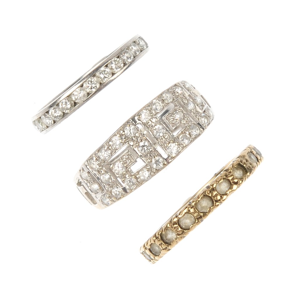 A selection of three diamond and gem-set rings.: A selection of three diamond and gem-set rings. To include a brilliant-cut diamond full-circle eternity ring, a colourless paste full-circle eternity ring, together with a colourless paste Greek-key d