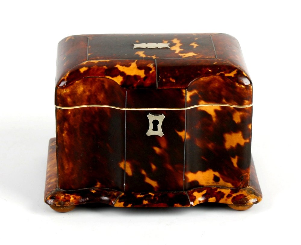 A 19th century tortoiseshell tea caddy: A 19th century tortoiseshell tea caddy, the whole of serpentine fronted design with metal inlaid line decoration, the hinged cover opening to reveal two lidded tea storage compartments, supported on f