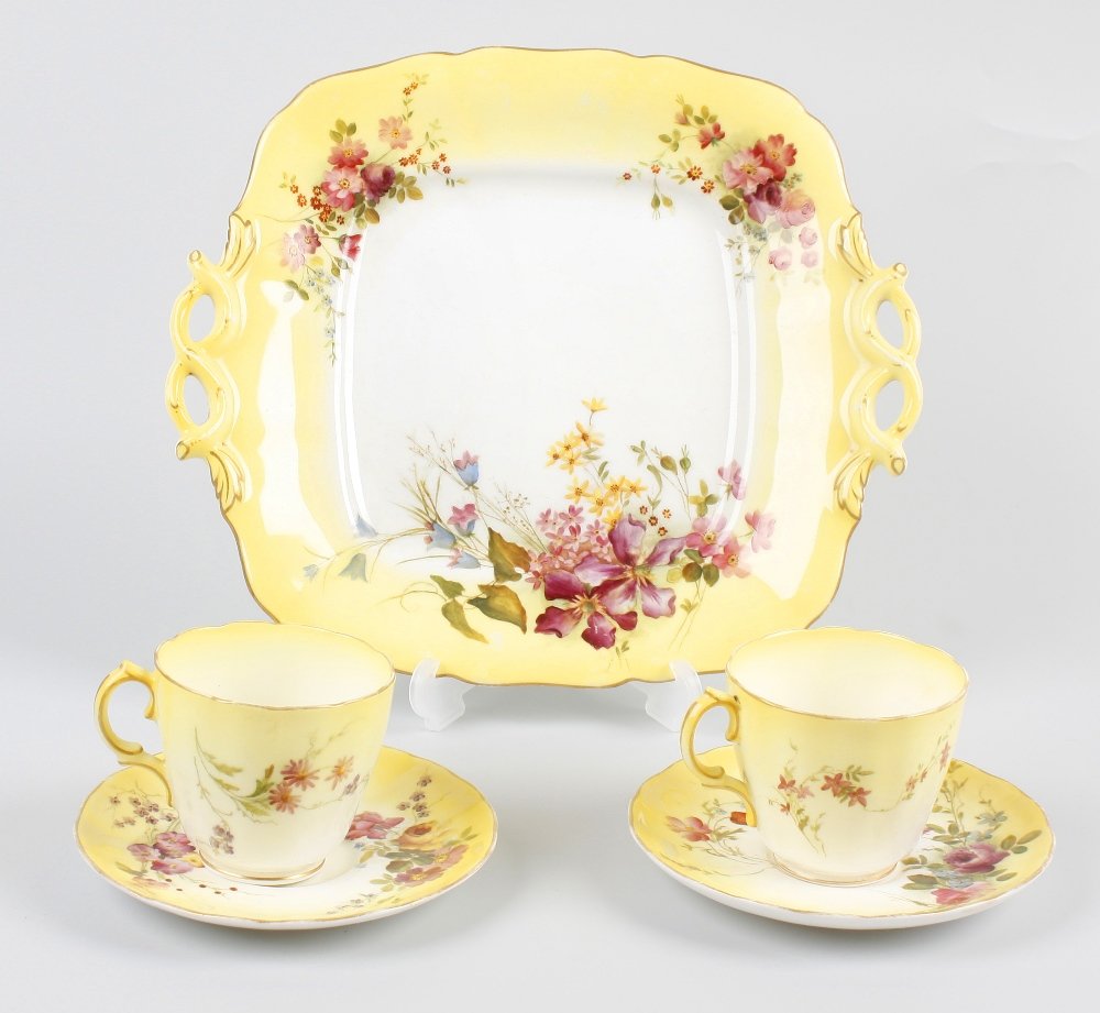 A box containing two Royal Worcester bone china tea cup: A box containing two Royal Worcester bone china tea cups, saucers and side plates, each with a merging yellow and white glazed ground with painted flowers, another side plate, a twin handled serving p