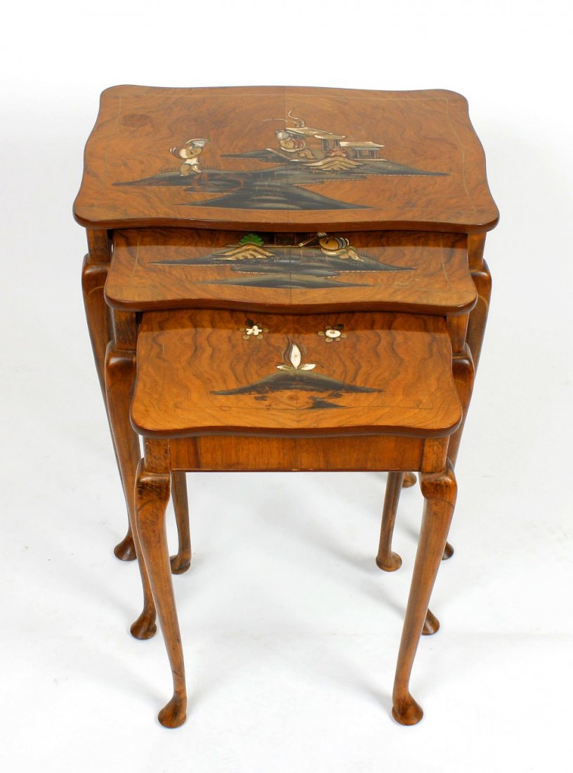 A nest of three stained wooden occasional tables: A nest of three stained wooden occasional tables, each of interlocking graduated form. The shaped tops decorated with oriental figures, the slender cabriole supports with hand painted gilded decoratio